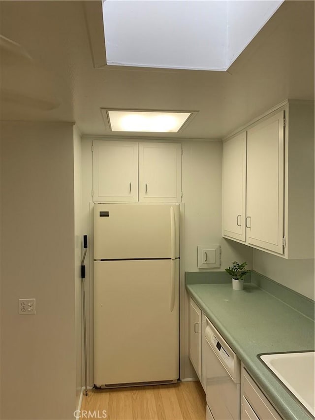 kitchen featuring white dishwasher, light wood-style flooring, white cabinets, light countertops, and freestanding refrigerator