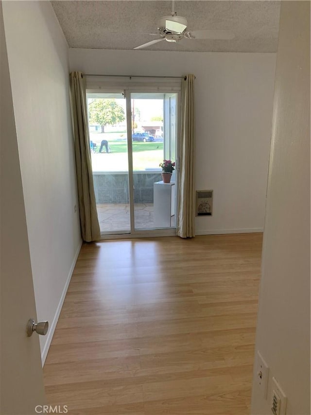 spare room featuring a textured ceiling, light wood-style flooring, and baseboards