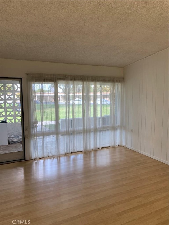 spare room with a textured ceiling and light wood-style floors