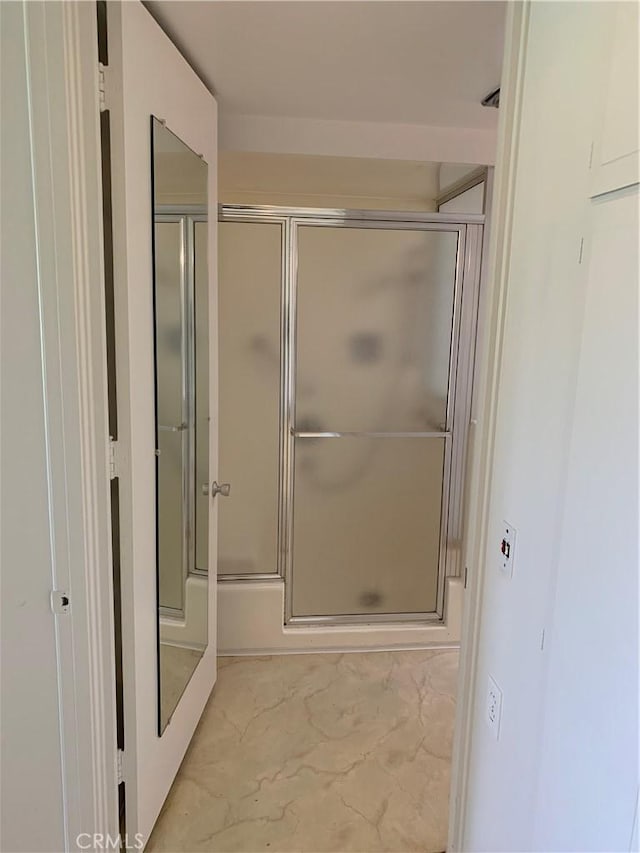 full bath featuring a shower with door and marble finish floor