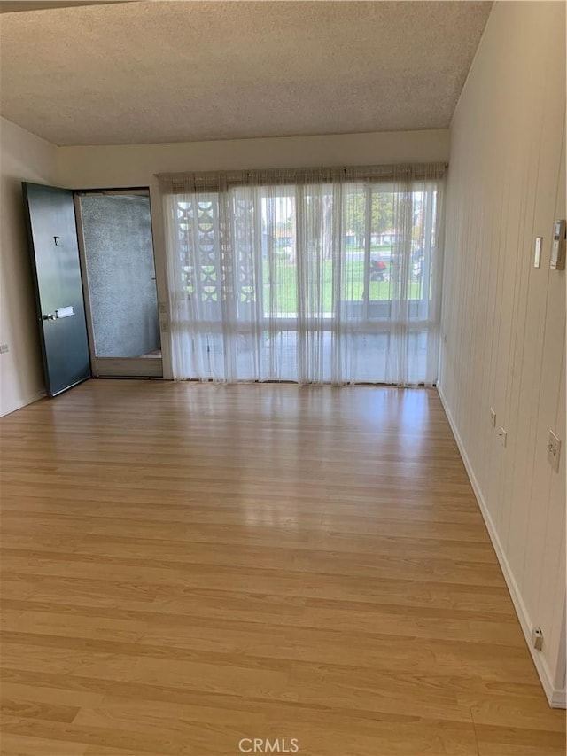 empty room with light wood-style flooring and a textured ceiling