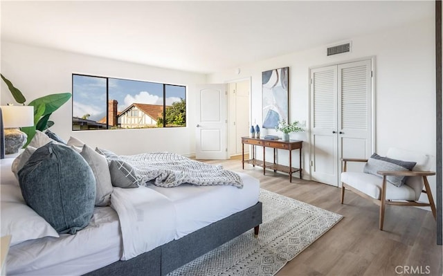 bedroom with a closet, visible vents, and wood finished floors