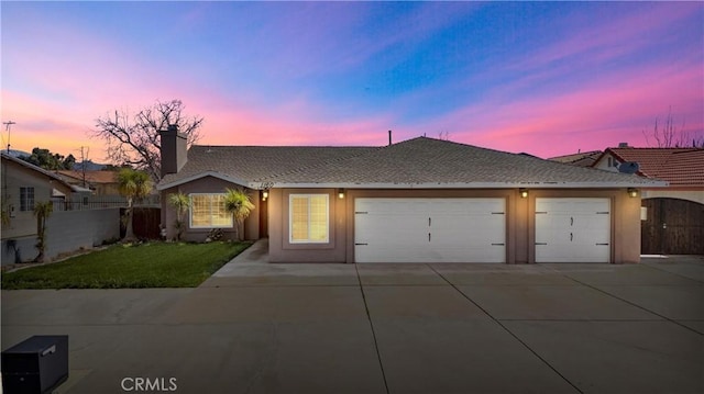 ranch-style house featuring concrete driveway, an attached garage, fence, and stucco siding