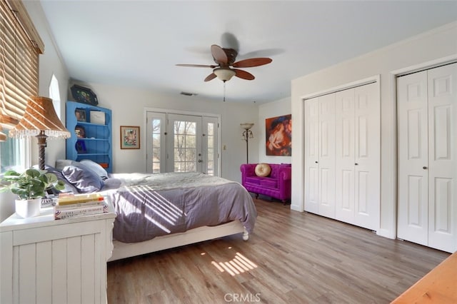 bedroom featuring visible vents, ceiling fan, wood finished floors, access to exterior, and multiple closets