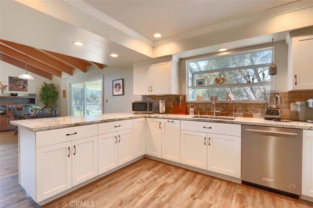 kitchen featuring light wood-style flooring, stainless steel appliances, a peninsula, a sink, and white cabinets