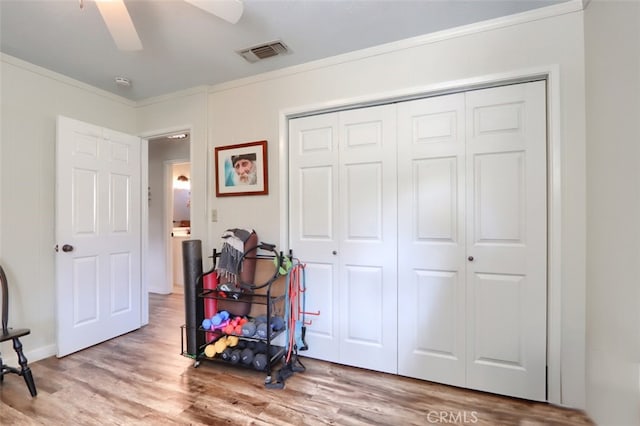 interior space featuring ornamental molding, wood finished floors, visible vents, and a ceiling fan