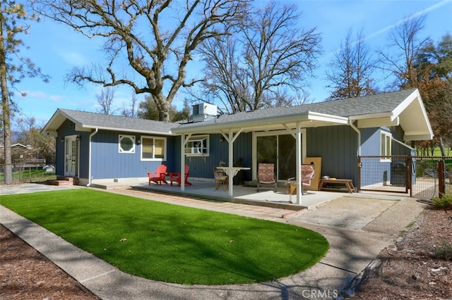 rear view of house with a lawn, a patio area, fence, and a gate