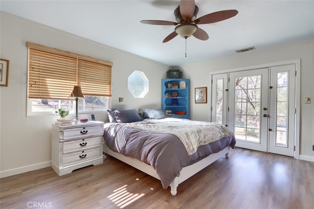 bedroom featuring access to outside, multiple windows, visible vents, and wood finished floors