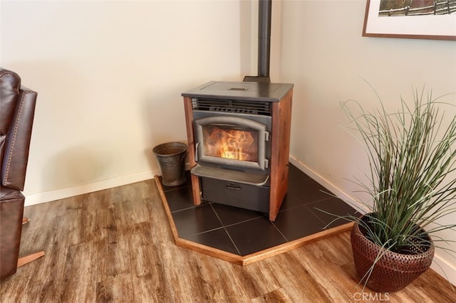 room details featuring wood finished floors, a wood stove, and baseboards