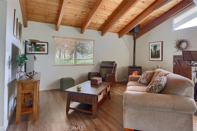 living room featuring vaulted ceiling with beams, wooden ceiling, wood finished floors, baseboards, and a wood stove