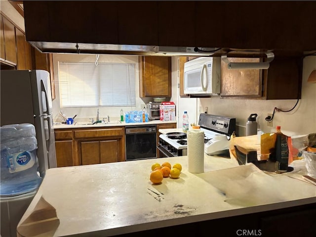 kitchen featuring white microwave, a sink, range with gas stovetop, black dishwasher, and light countertops