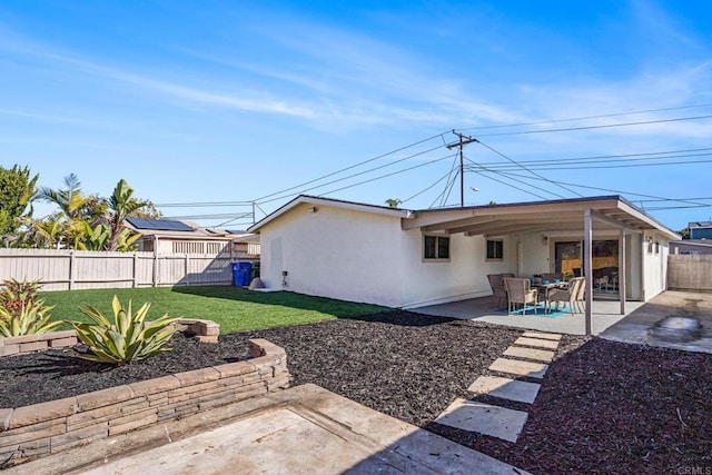 back of house with a patio area, a lawn, a fenced backyard, and stucco siding