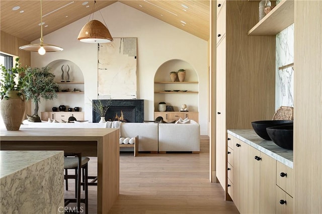 interior space with light wood-type flooring, a warm lit fireplace, wood ceiling, and built in features