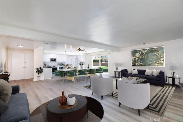 living room featuring visible vents, light wood-type flooring, and ceiling fan