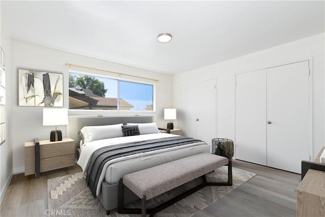 bedroom featuring light wood-type flooring and multiple closets