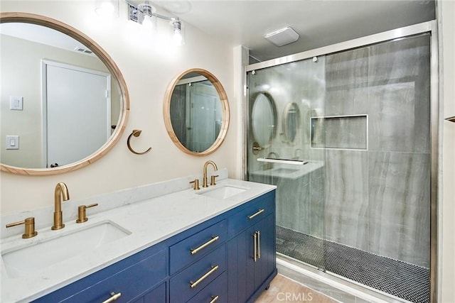 full bath with double vanity, a stall shower, and a sink