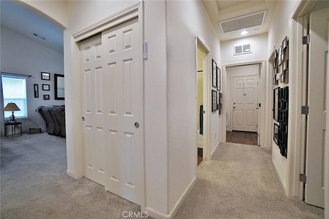 hall featuring light carpet, visible vents, and attic access