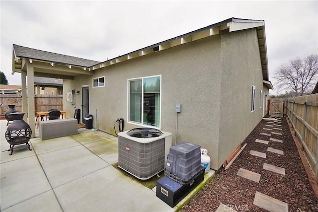 rear view of house featuring a patio area, central AC, a fenced backyard, and stucco siding