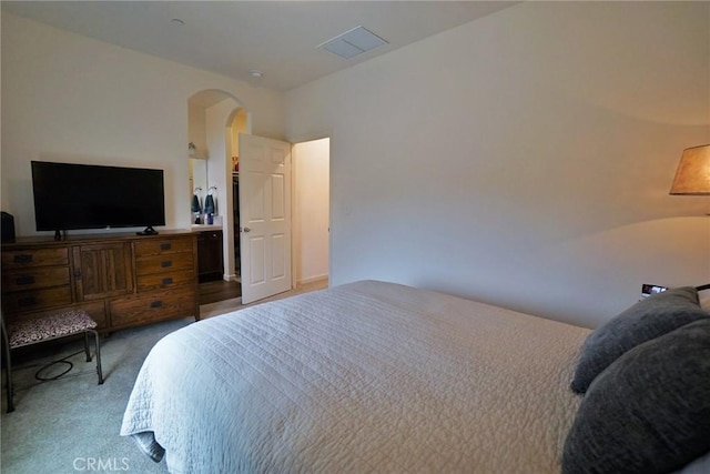 carpeted bedroom featuring arched walkways and visible vents