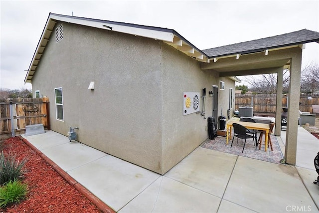 view of home's exterior featuring a patio area, a fenced backyard, outdoor dining space, and stucco siding