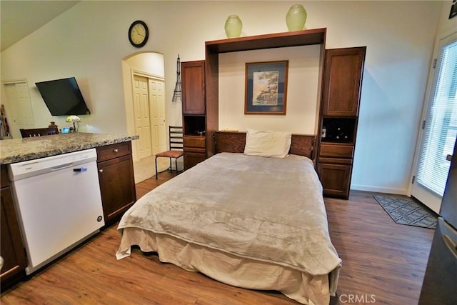 bedroom featuring dark wood-style floors, arched walkways, multiple windows, and vaulted ceiling