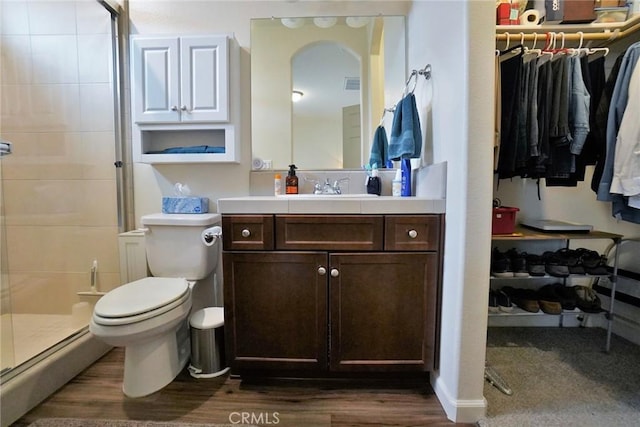 full bath featuring a spacious closet, wood finished floors, a shower stall, and vanity