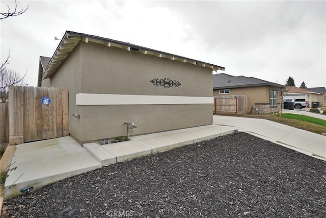 view of side of property featuring fence and stucco siding