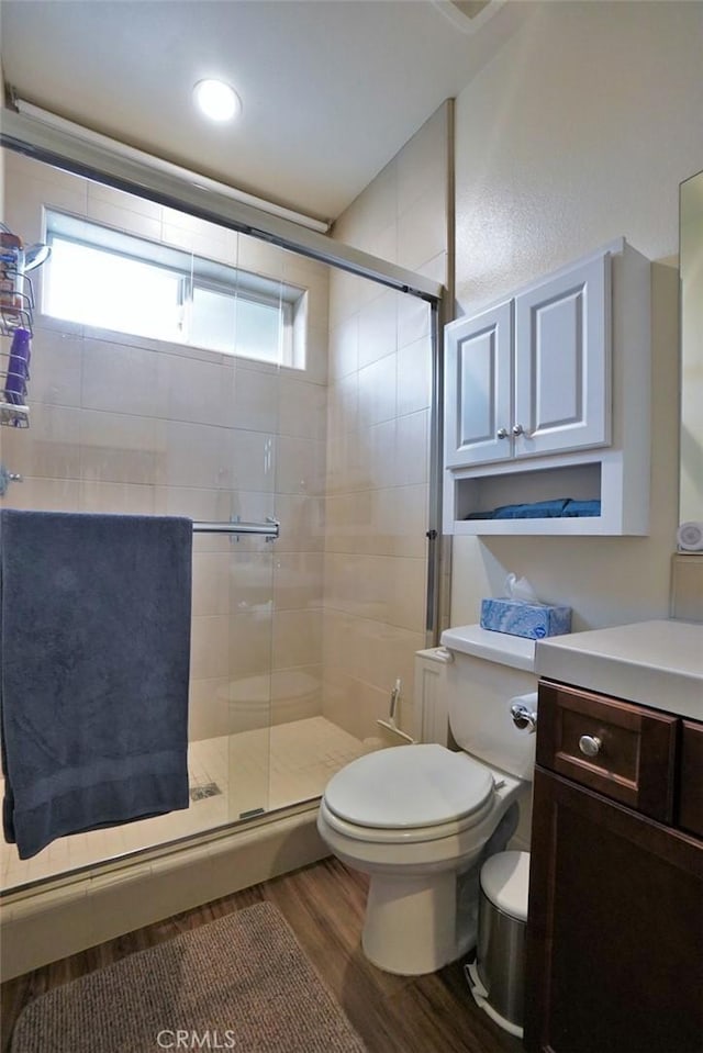 full bathroom with a healthy amount of sunlight, a stall shower, toilet, and wood finished floors