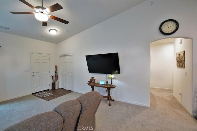 living area featuring baseboards, arched walkways, a ceiling fan, light colored carpet, and lofted ceiling