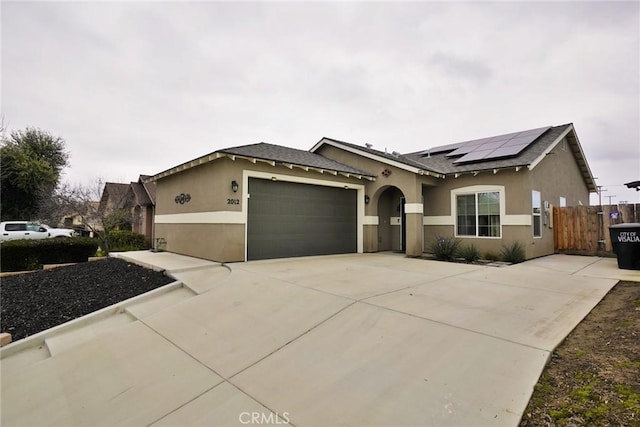 ranch-style house with concrete driveway, stucco siding, an attached garage, and solar panels