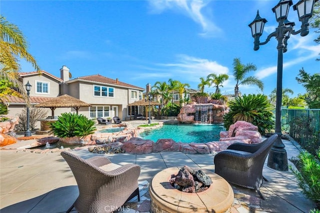 outdoor pool featuring a patio area, an outdoor fire pit, fence, and a jacuzzi