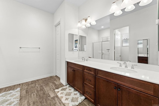 bathroom featuring double vanity, baseboards, a sink, and wood finished floors