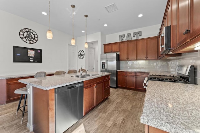 kitchen with appliances with stainless steel finishes, a breakfast bar, a sink, and an island with sink