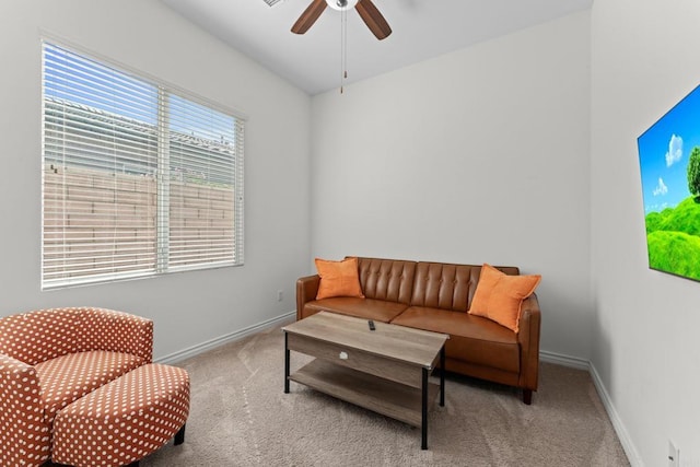 living room featuring a ceiling fan, light colored carpet, and baseboards