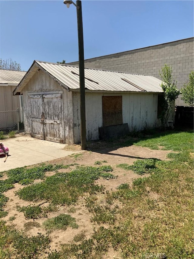 view of side of property with metal roof, an outdoor structure, and fence