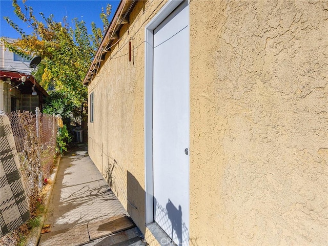 view of side of home with fence and stucco siding