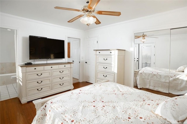 bedroom featuring wood finished floors, a ceiling fan, a closet, ensuite bath, and crown molding