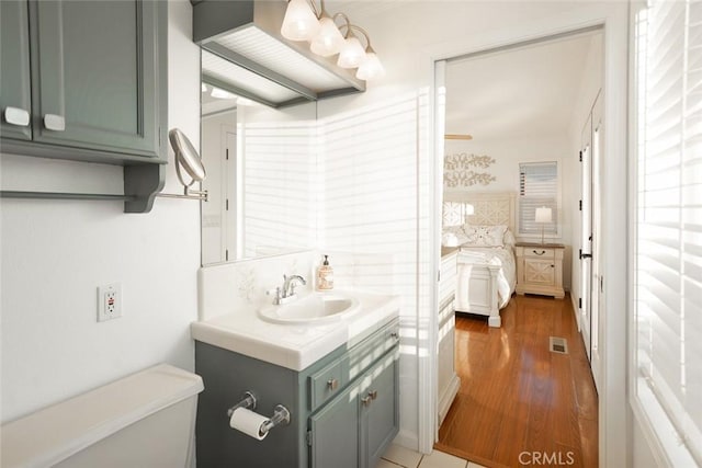 bathroom with visible vents, vanity, decorative backsplash, and wood finished floors