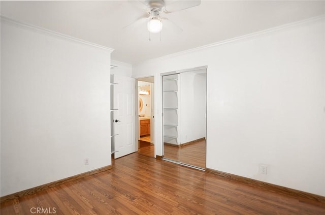 unfurnished bedroom featuring a closet, ornamental molding, ceiling fan, wood finished floors, and baseboards