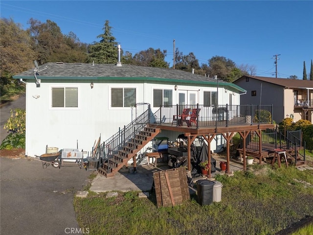 back of house with stairs, a patio, a deck, and roof with shingles