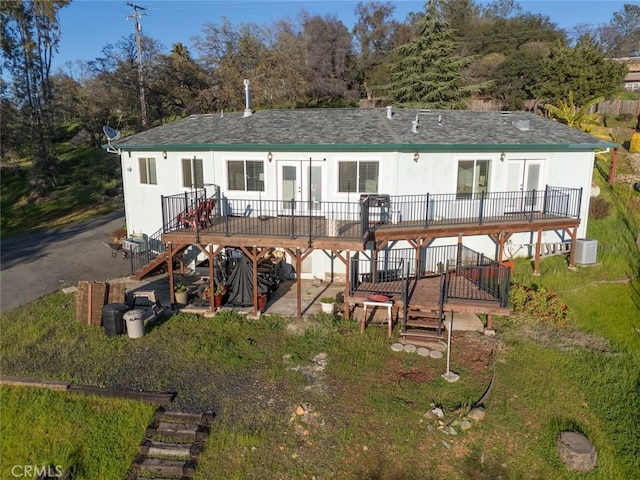 rear view of house featuring a shingled roof, stairway, and a wooden deck