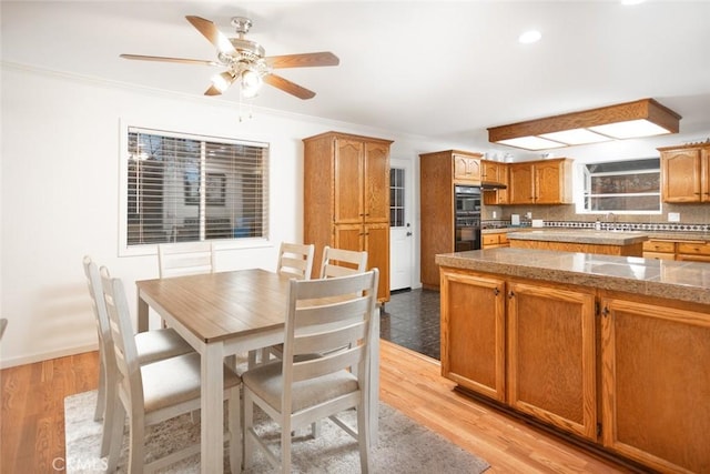 interior space with ornamental molding, ceiling fan, light wood finished floors, and baseboards