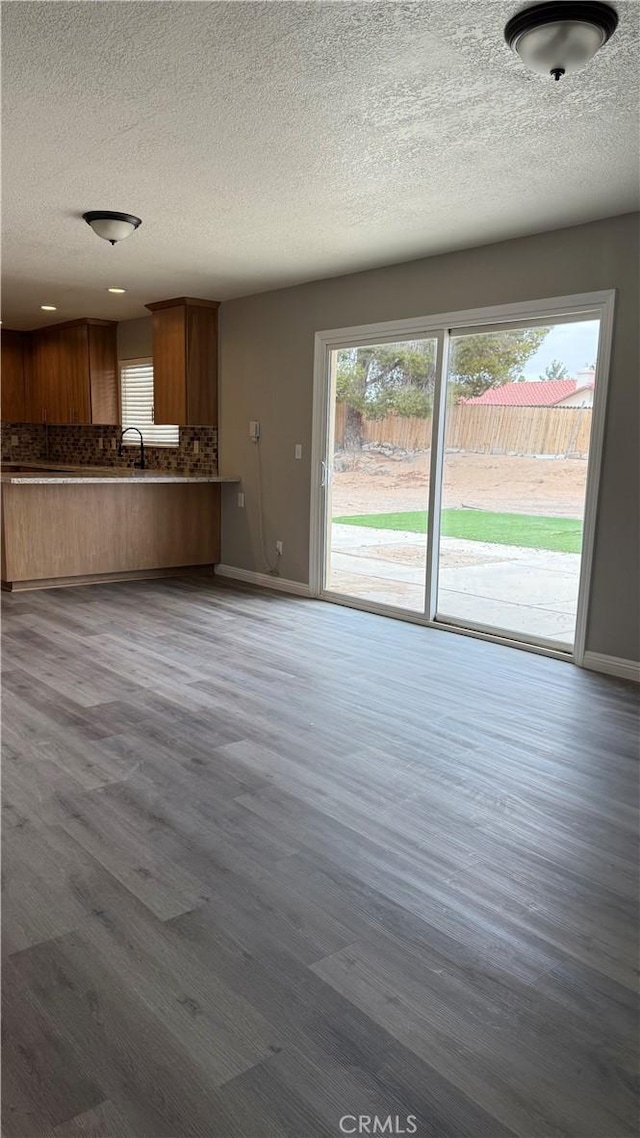 unfurnished living room featuring a textured ceiling, baseboards, and dark wood-type flooring