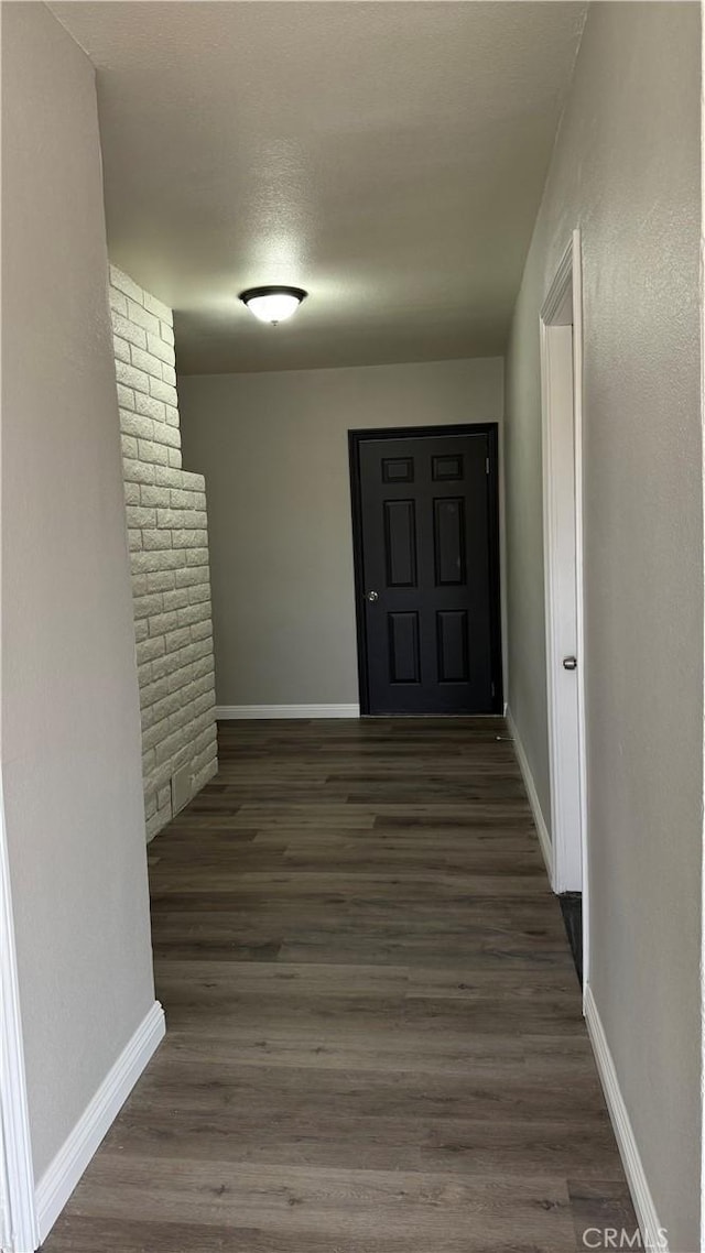 corridor with dark wood-style flooring and baseboards