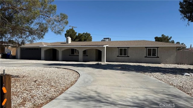 ranch-style house with driveway, a garage, fence, and stucco siding