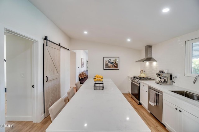 709 Greenbank Ave, Duarte, CA 91010 - kitchen featuring a barn door, appliances with stainless steel finishes, wall chimney range hood, white cabinetry, and a sink