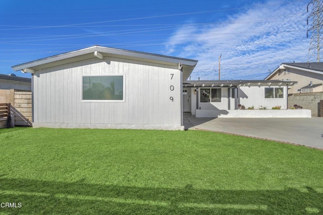 view of front of house featuring a front yard, fence, and a patio