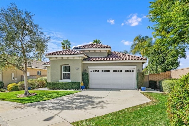 mediterranean / spanish home featuring concrete driveway, stucco siding, an attached garage, fence, and a front yard