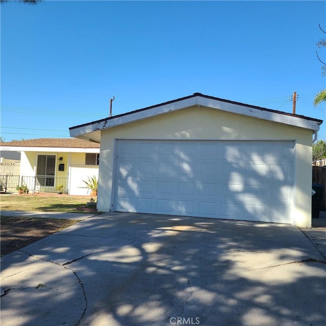 view of front facade with a garage, concrete driveway, fence, and stucco siding