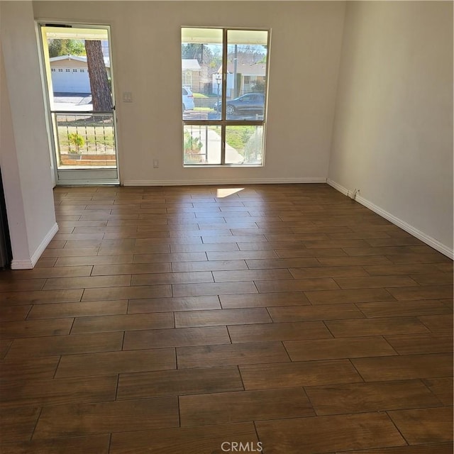 unfurnished room with dark wood finished floors and baseboards